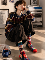 Person wearing colorful socks sitting on the floor with books and a cup in the background