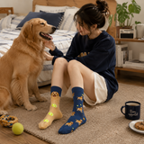 Woman sitting on the floor with a dog, wearing socks with dog patterns, in a home setting.
