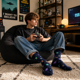 Person sitting on a bean bag chair playing video games in a room with gaming decor.