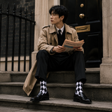 Man in trench coat reading a newspaper on steps