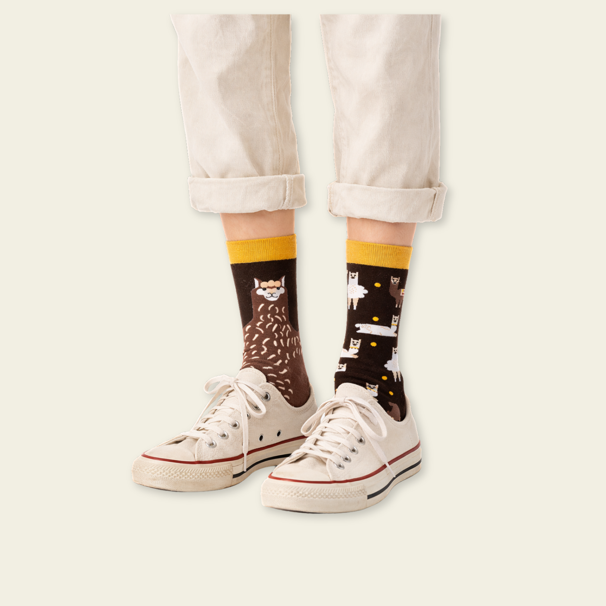 Person wearing socks with cat designs and white sneakers on a plain background