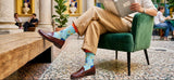 Person sitting in a chair wearing patterned socks with a cityscape design, in an indoor setting.